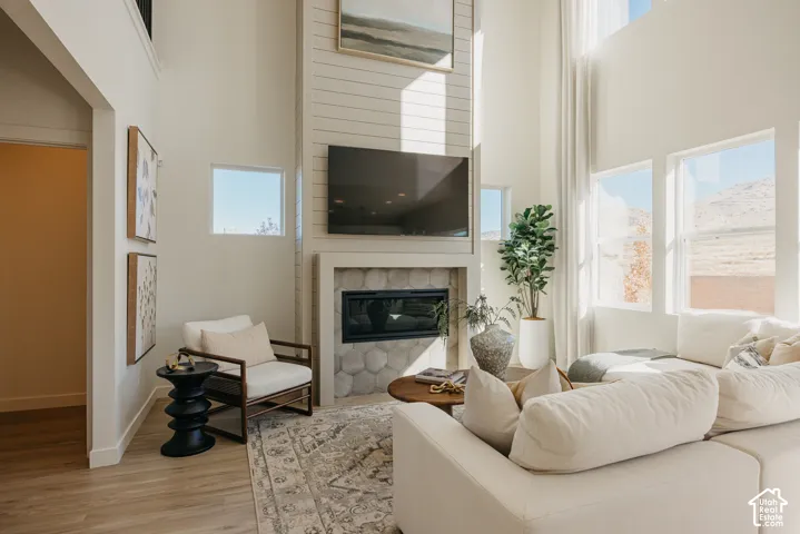 Vaulted ceilings, wood-finish flooring, a contemporary fireplace with hexagonal tile, and abundant natural light from multiple windows