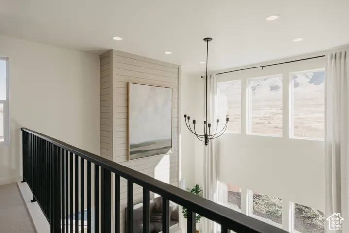Open ceiling height with recessed lighting, shiplap accent wall, contemporary black metal railing, and a modern candelabra chandelier