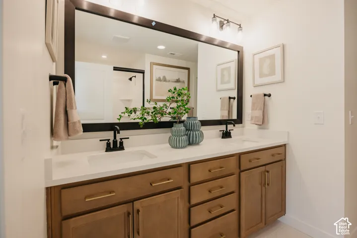 Dual vanity with white countertops, wood-finish cabinetry, matte black fixtures, and a large framed mirror