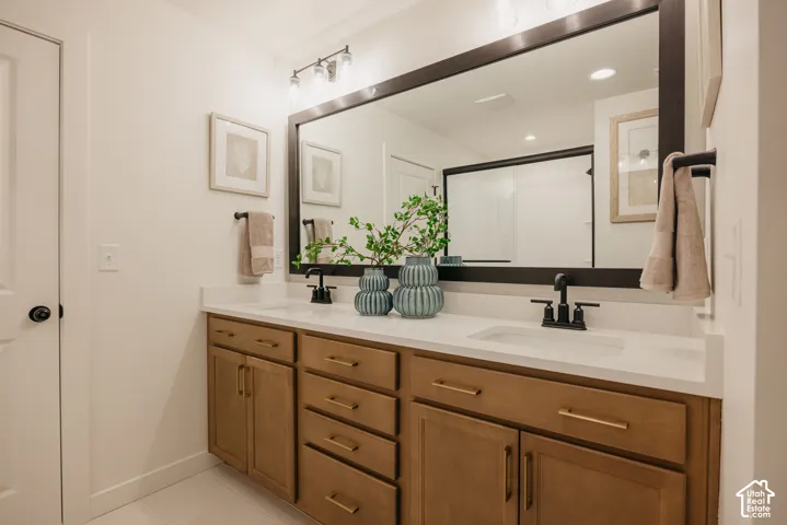 Dual vanity with light wood-finish cabinetry, gold-tone hardware, and white countertops