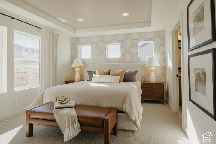 Recessed lighting, tray ceiling, patterned accent wall, large windows, wood-finish nightstands