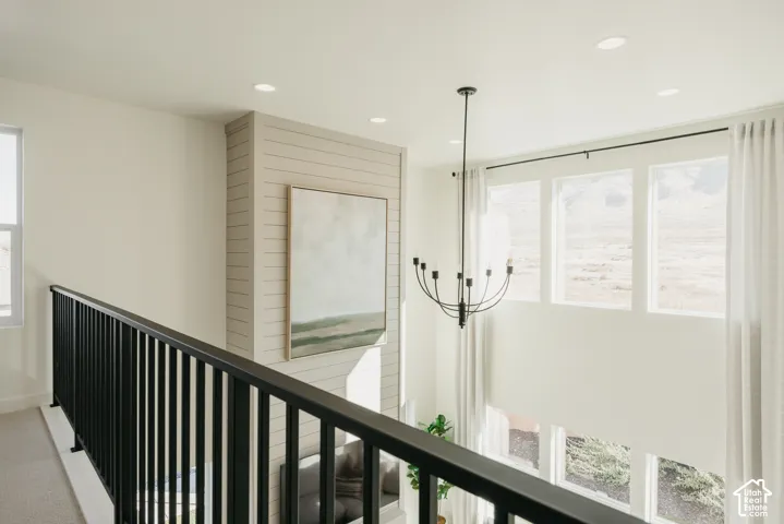Open-concept living space with shiplap wall accent, large windows, recessed lighting, and a contemporary chandelier