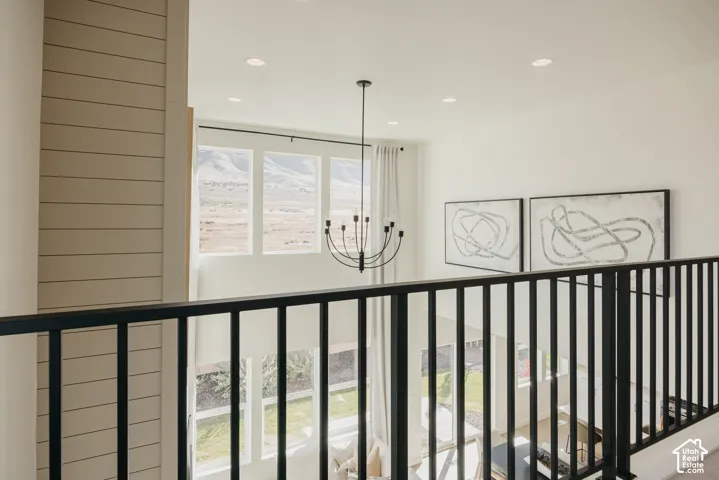 Open loft area with black metal railing, shiplap accent wall, recessed lighting, and a modern chandelier