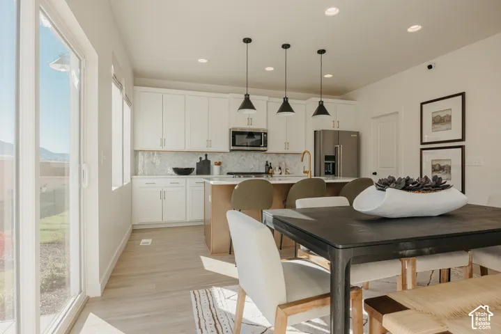 Open concept living space featuring wood-finish flooring, white cabinetry, a kitchen island with seating, and stainless steel appliances