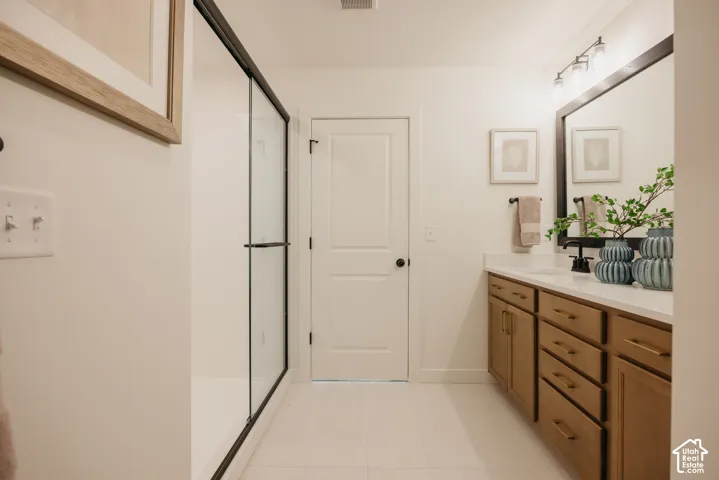 Glass-enclosed shower with black trim, wood-finish vanity with ample storage, integrated sink, and white countertop