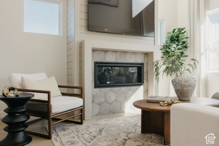 Integrated fireplace with hexagonal tile surround, elevated flat screen placement, shiplap accent wall, and high transom window
