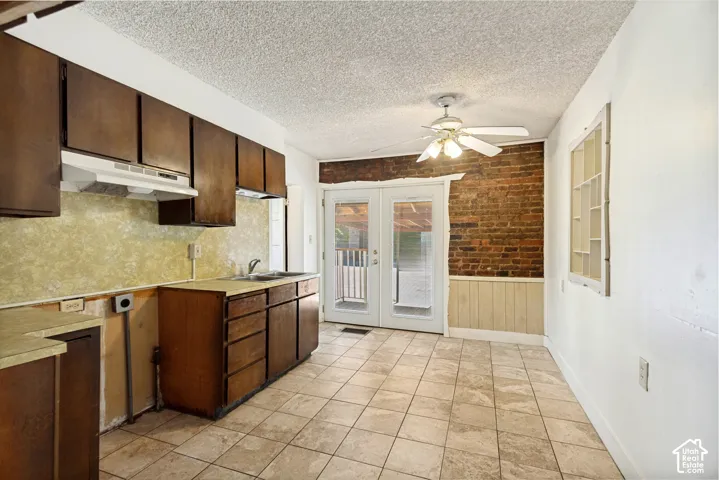 Kitchen featuring wood-finish cabinetry, tile flooring, and exposed brick accent wall