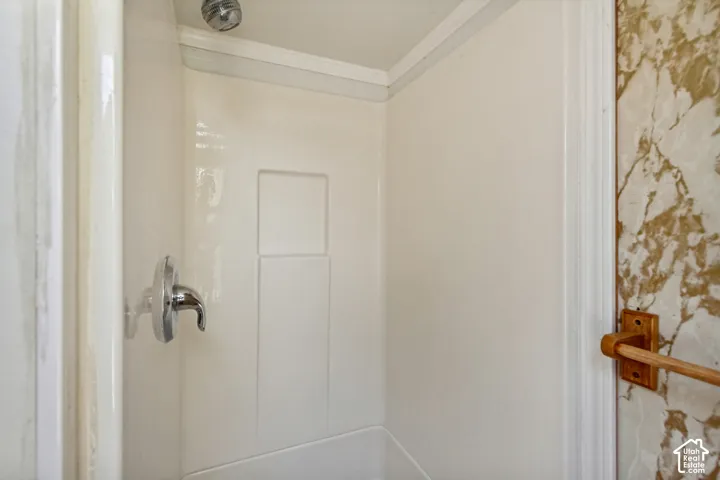 Shower stall with chrome fixtures, integrated soap dish, and surrounding wall with a faux-marble finish