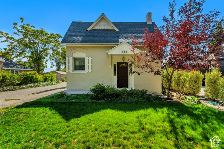 Gabled roofline with dark shingles, light-colored exterior, and a prominent front entry with an overhang