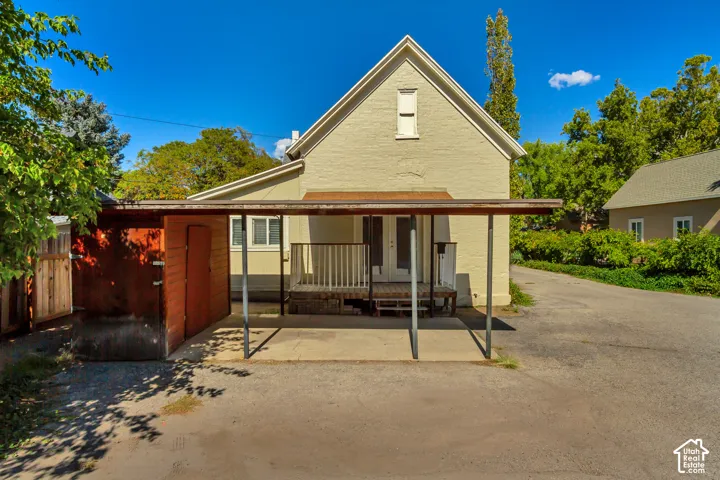 Carport structure with metal supports, wood-paneled exterior storage, and a rear deck