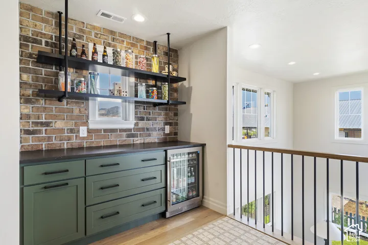 Custom built-in cabinetry with matte black hardware, integrated beverage refrigerator, open shelving, and exposed brick accent wall