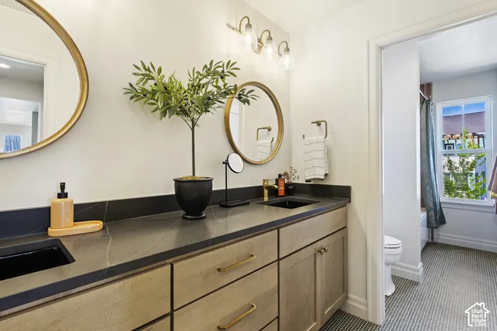 Dual vanity featuring wood cabinetry, dark countertops, and undermount sinks