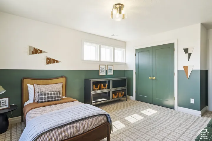 Dual-tone wall treatment, built-in double-door closet, window with natural light, patterned carpeting, and a semi-flush mount ceiling light fixture