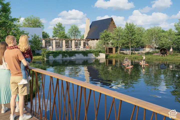 Wood-finish railing with geometric metal balusters, overlooking a body of water with a distinct structure featuring a dark-pitched roof and a prominent chimney
