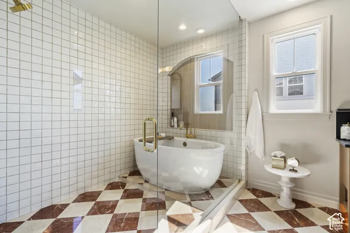 Freestanding bathtub within a glass-enclosed wet room, featuring a rain showerhead