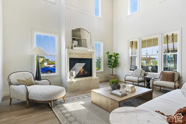 Two-story living area featuring a fireplace with a stone surround, wood-finish flooring, and multiple windows