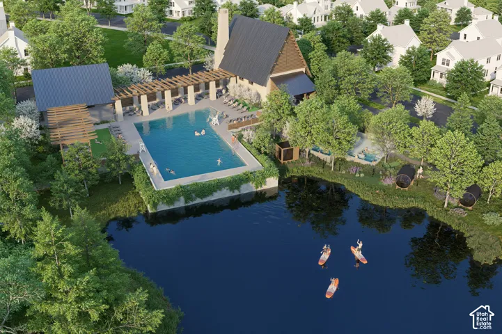 Expansive outdoor pool area with shaded lounging, adjacent clubhouse building, and lakeside setting