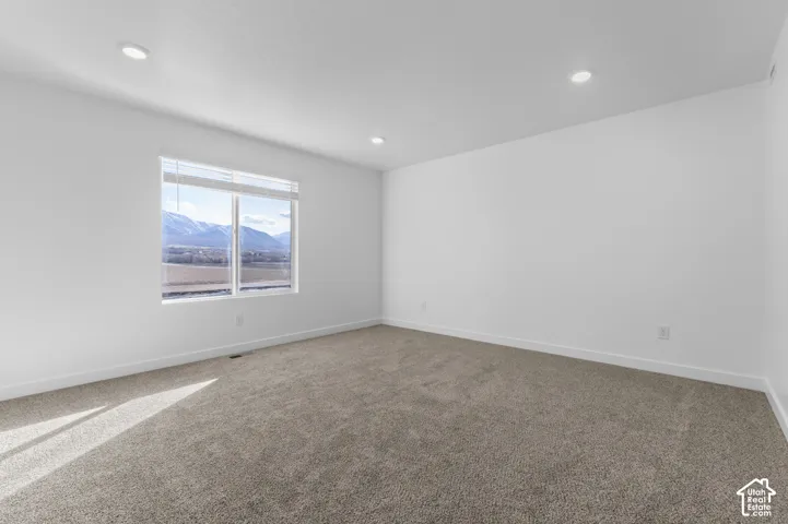 Recessed lighting illuminates the neutral-toned carpeting and white walls