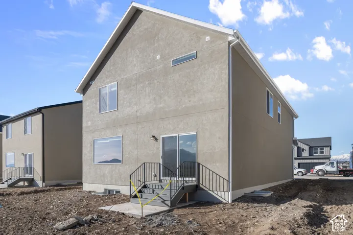Stucco exterior featuring multiple windows, a sliding glass door, and a exterior staircase with metal railing
