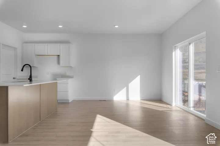 Open-concept living area featuring wood-finish flooring, white walls, recessed lighting, and a sliding glass door