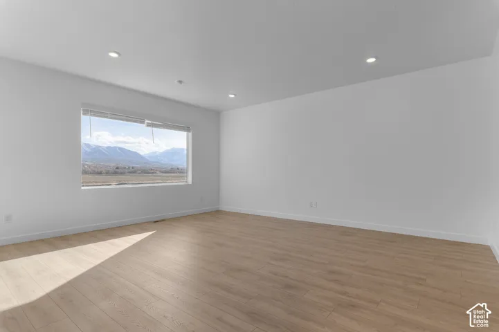 Spacious interior with wood-finish flooring, recessed lighting, and a large window offering expansive mountain scenery