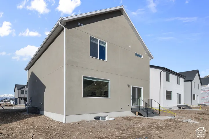 Stucco exterior with a pitched roof, featuring multiple windows and a sliding glass door with an exterior staircase