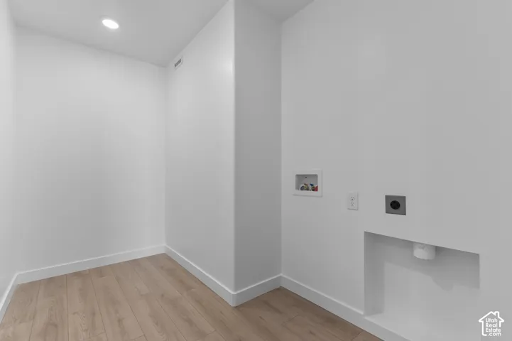 Laundry area featuring wood-finish flooring, recessed lighting, and white walls