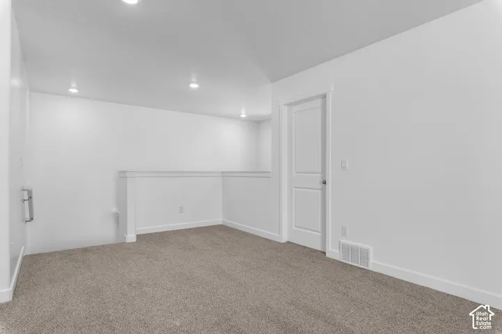 Recessed ceiling lighting, light gray carpeting, white painted walls, white interior door, and white railing