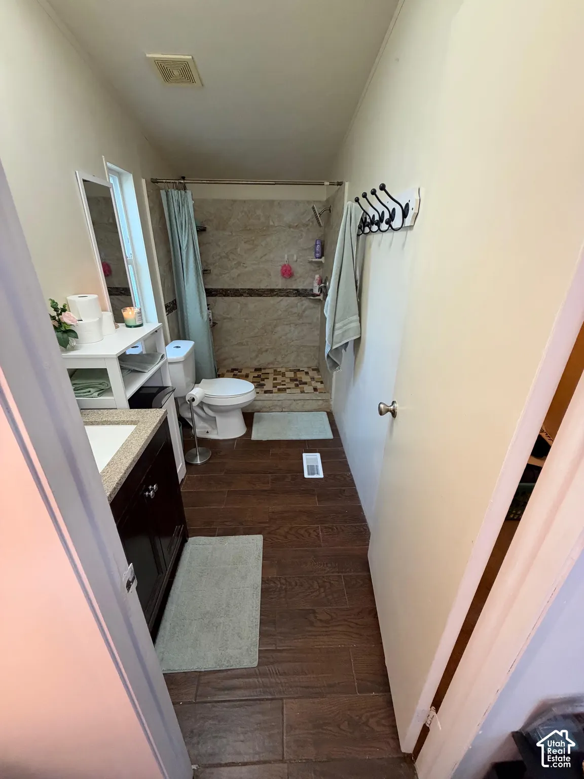 Wood-finish tile flooring, walk-in shower with tiled walls, vanity with a countertop, and a built-in cabinet