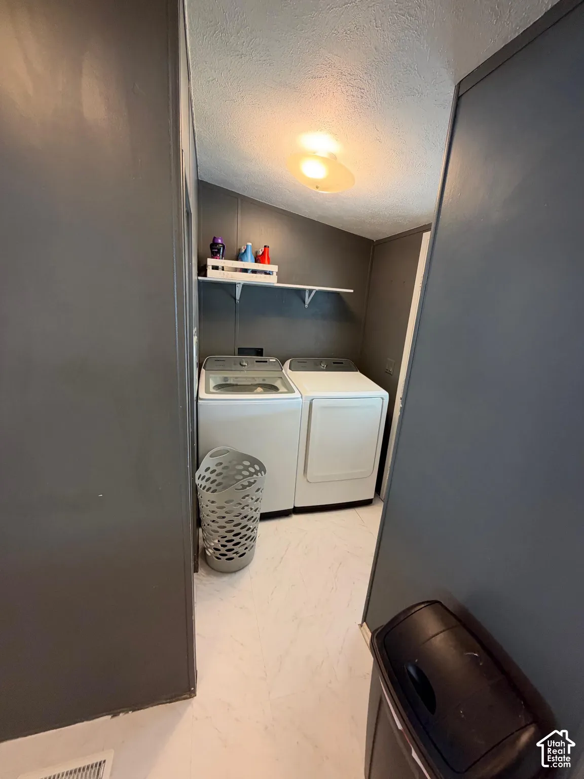 Laundry area featuring a sloped ceiling, overhead lighting, and wall-mounted shelving