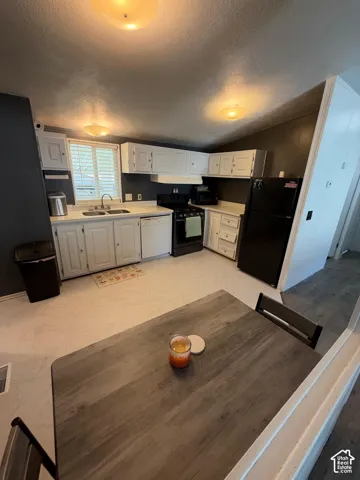 Kitchen with white cabinetry, light countertops, and a stainless steel double basin sink
