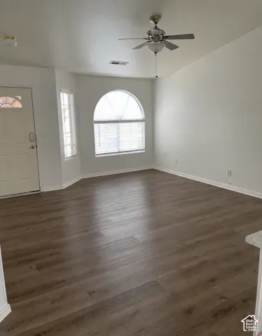 Interior space featuring wood-finish flooring, vaulted ceilings, a prominent arched window, and a brushed nickel ceiling fan