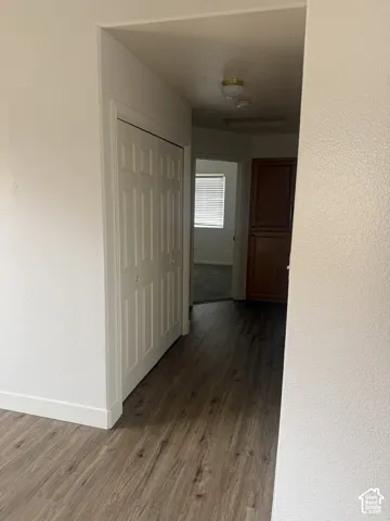 Hallway featuring wood-finish flooring, white paneled bi-fold closet doors, built-in wooden cabinetry, and neutral wall tones