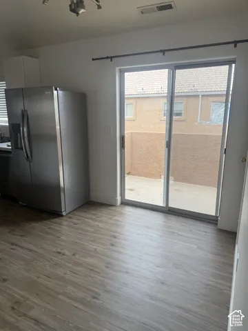 Stainless steel side-by-side refrigerator, sliding glass patio door, and wood-finish flooring
