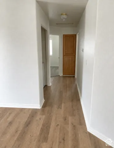Hallway featuring wood-finish flooring, white walls, and a built-in wood-paneled cabinet