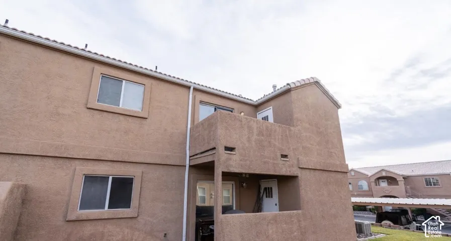 Stucco exterior with multiple windows, an upper-level balcony, and a covered entry