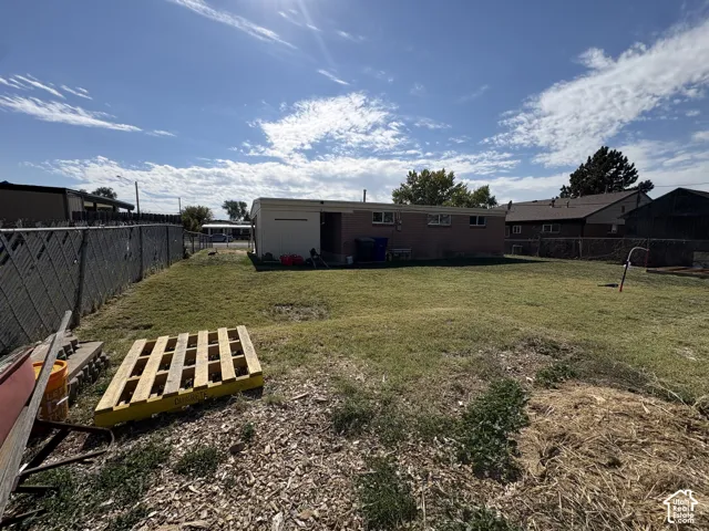Expansive backyard featuring a chain-link fence, a storage shed, and a brick exterior