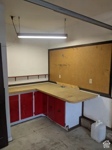 Built-in workbench with storage cabinetry, integrated pegboard wall, and overhead fluorescent lighting