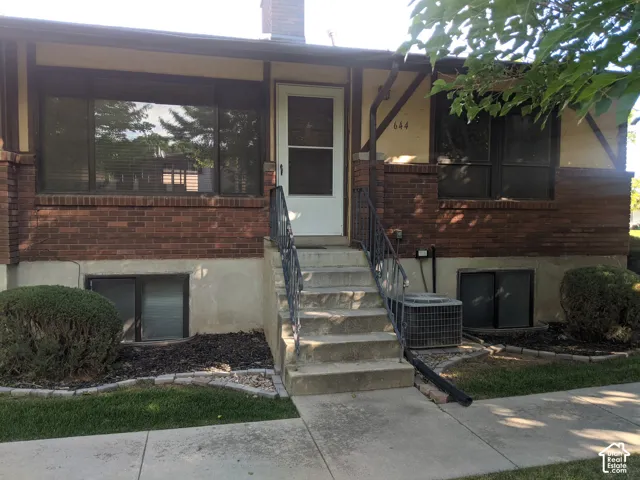 Brick exterior with gabled architectural details, concrete walkway, and established landscaping