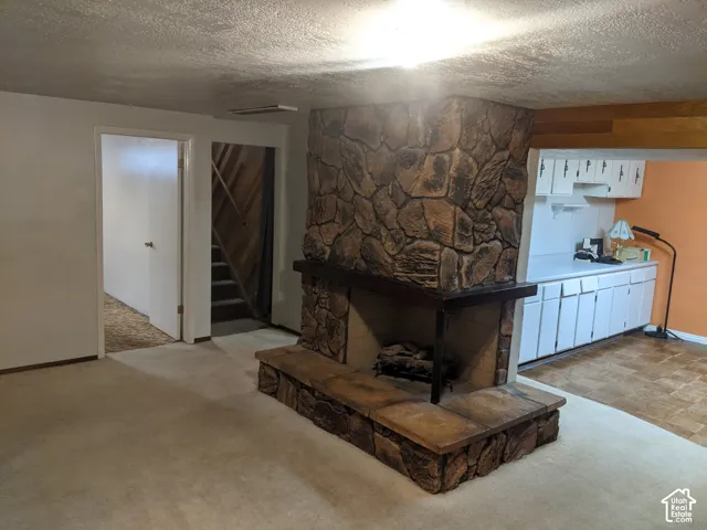 Stone-clad fireplace with hearth, white cabinetry, and wood-finish flooring
