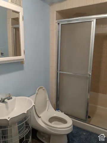 Bathroom featuring a ceramic pedestal sink, toilet with elongated bowl, tile flooring, and a frameless glass shower enclosure with brushed nickel hardware and tile surround