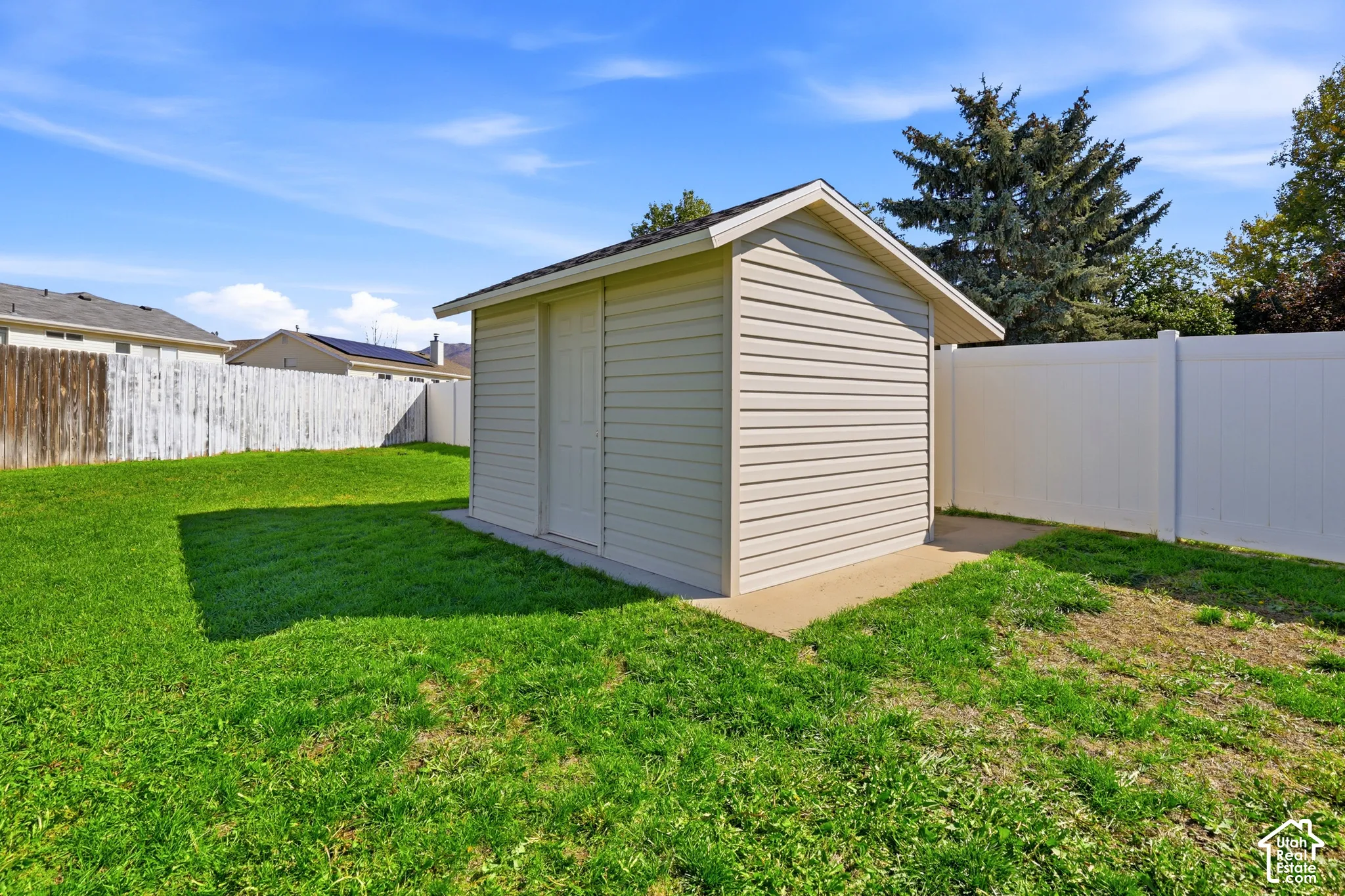 Detached storage shed featuring vinyl siding and a shingled roof, set on a concrete pad