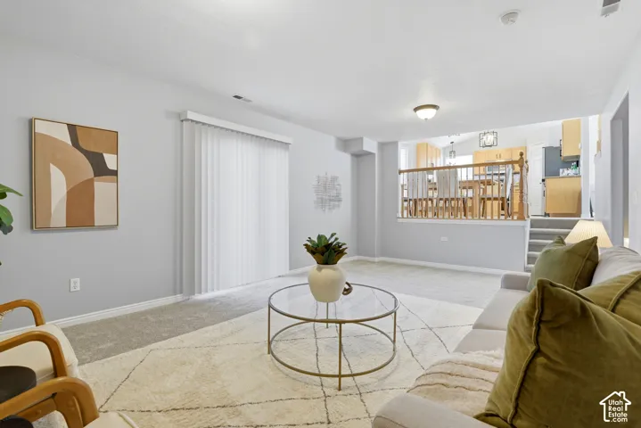 Carpeted living area with light gray wall paint, featuring a glass sliding door with vertical blinds