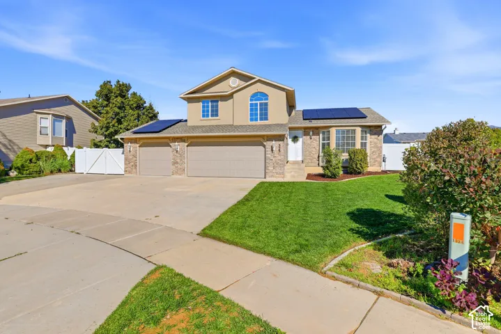 Two-story residence featuring a two-car garage, solar panels, and a concrete driveway