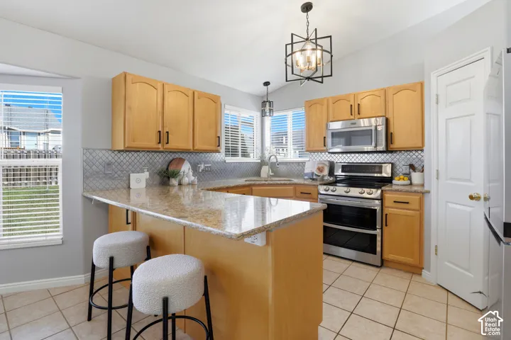 Kitchen featuring wood cabinetry, stainless steel appliances, a tiled backsplash, and granite countertops
