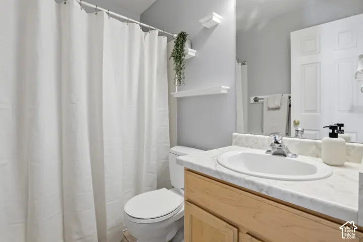Vanity with a white oval sink, chrome faucet, and light-toned wood-finish cabinetry