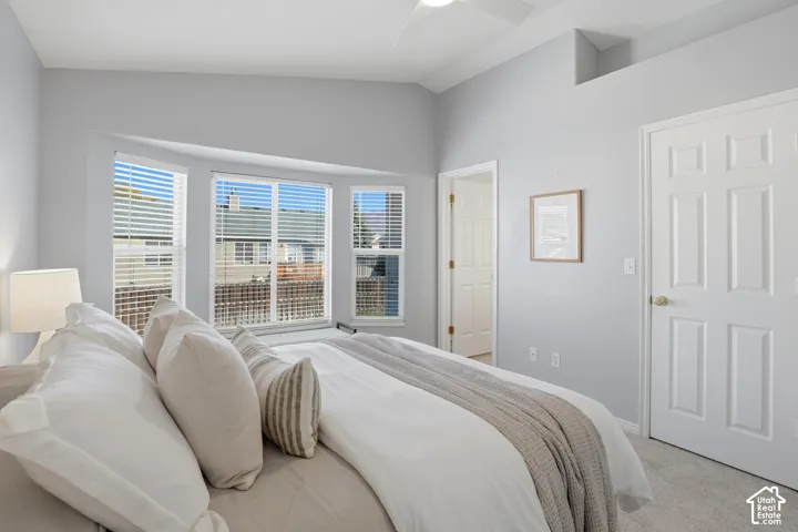 Bay window with horizontal blinds, neutral wall paint, vaulted ceiling, and carpeted flooring