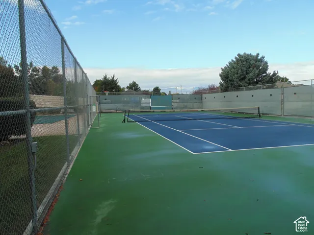 Private tennis court featuring a hard surface, perimeter chain-link fencing, and integrated wind screening