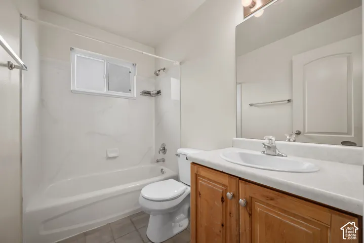 Bathroom featuring a wood-finish vanity with an integrated sink, shower-tub combination, and tiled flooring