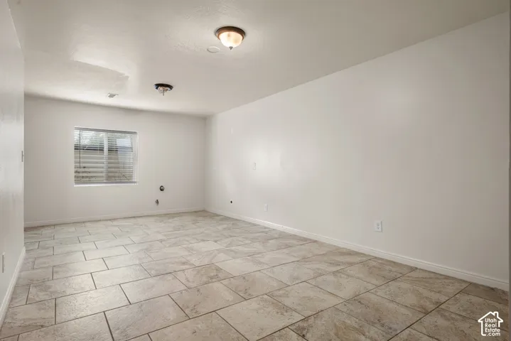 Spacious room featuring tile flooring, white walls, and a window for natural light